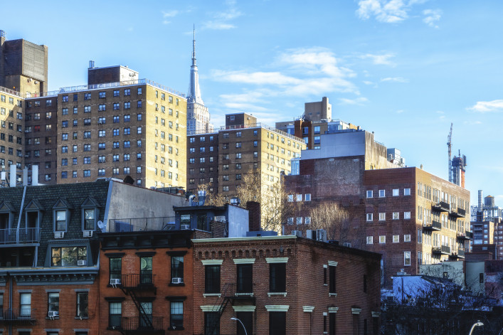 A street view of apartment buildings with the Empire State Building in the background at the High Line