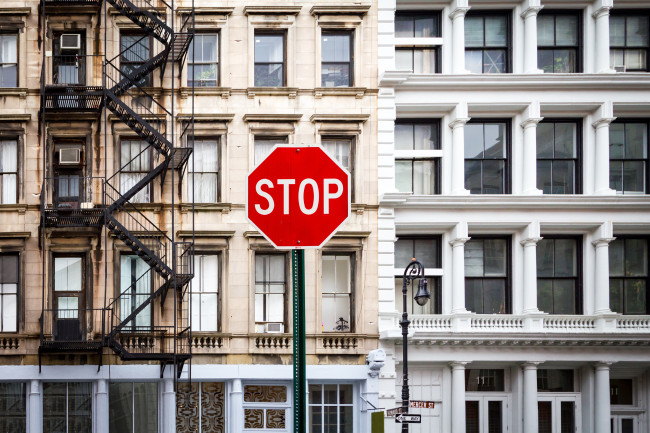 A photo of a stop sign in front of an NYC apartment building.