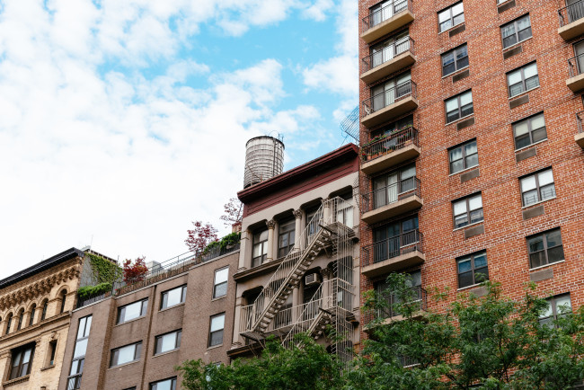 Cityscape of Manhattan with old buildings and water tower against sky