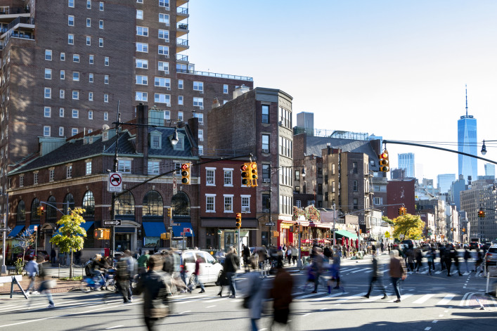 Busy crowds of people walking across the street at 7th Avenue in the Greenwich Village neighborhood of New York City NYC