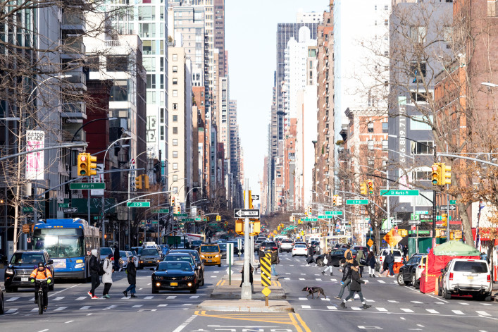 Busy intersections along 3rd Avenue are crowded with crowds of people and cars during rush hour traffic in the East Village neighborhood of Manhattan