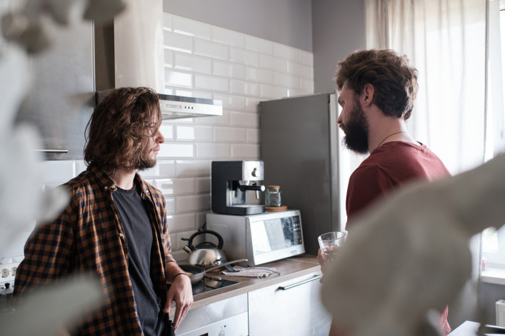 Man talking to his friend in the kitchen.