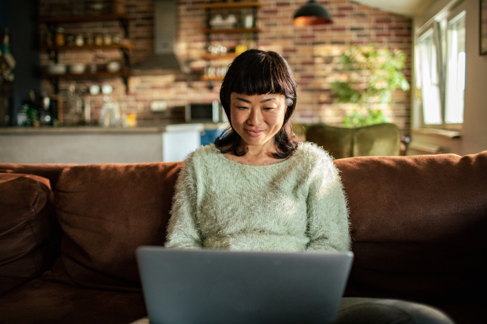 Close up of a young Japanese woman using a laptop on a couch in the living room