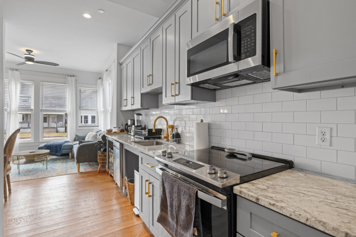 A kitchen with stainless steel appliances and counter tops and wood floor 