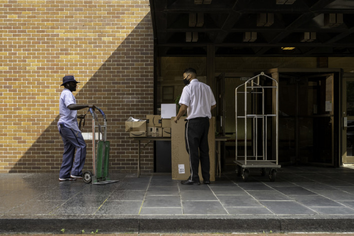 Postman transferring packages to the doorman of a residential building on Madison Avenue