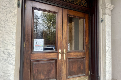 Wooden double entry doors of NYC apartment building Brooklyn with B grade energy efficiency notice