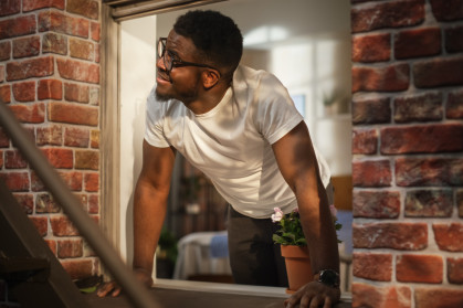 Man opening window in brick apartment building