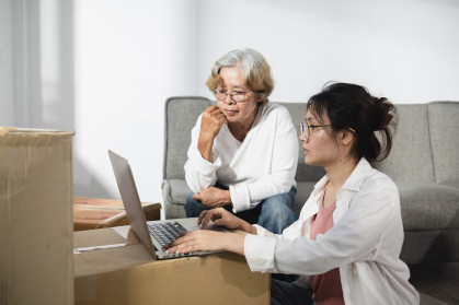 The concept of moving rooms and new houses, Asian teenage and elderly women, mother and daughter are chatting During the use of the laptop. stock photo