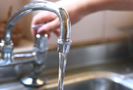 faucet with hand of woman in kitchen for cleaning, drinking and washing dishes. Interior, steel and household plumbing with sink and tap at home for stream, flowing and splash