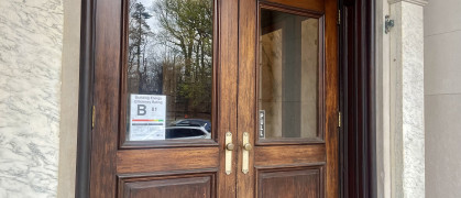 Wooden double entry doors of NYC apartment building Brooklyn with B grade energy efficiency notice