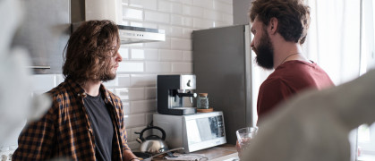 Man talking to his friend in the kitchen.