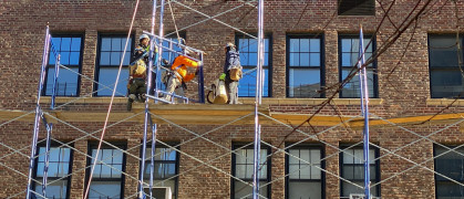 Four workmen in safety gear rig scaffolding in front of a Manhattan apartment building in 2022.