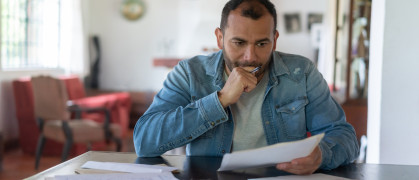 A man looks over several documents and looks concerned.