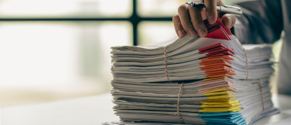 Businessman working in finance with pile of unfinished papers on the desk business paper pile stock photo