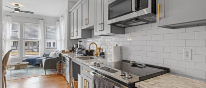 A kitchen with stainless steel appliances and counter tops and wood floor