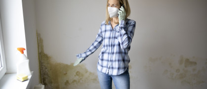 Woman standing in front of wall with mold and talking on cell phone stock photo