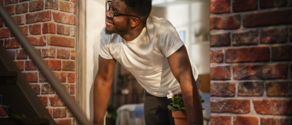 Man opening window in brick apartment building