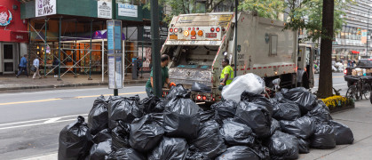 DSNY truck takes away black trash bags on an NYC street