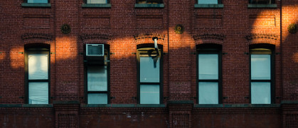 A ray of sunlight hits the red brick facade with blue windows of apartment buildings in New York