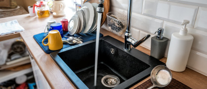 Water flowing out of a kitchen stainless steel tap into the sink.